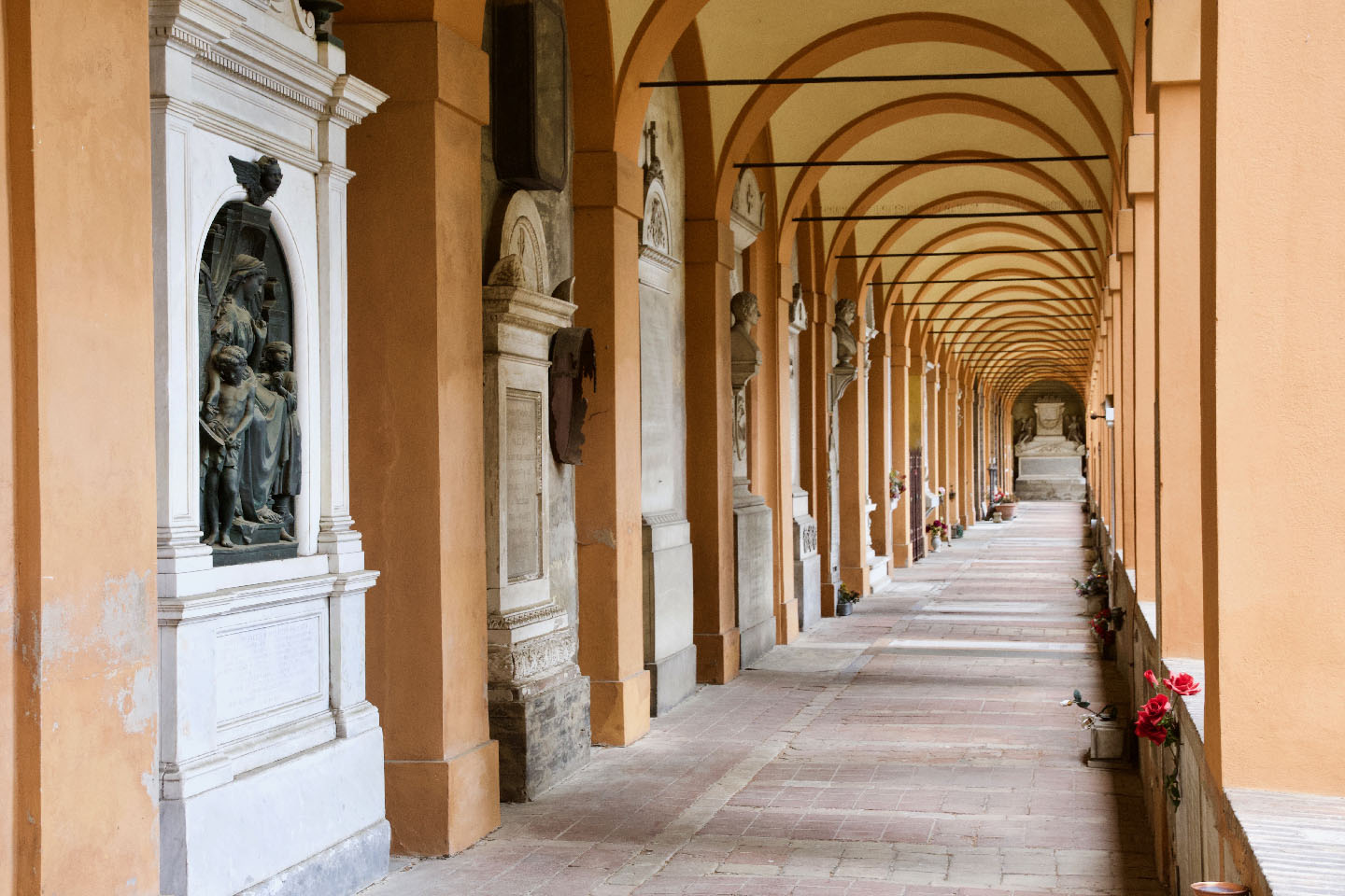 Il chiostro maggiore del Cimitero della Certosa di Bologna. Si vede una serie di archi di portico, e monumenti sepolcrali sulla sinistra.