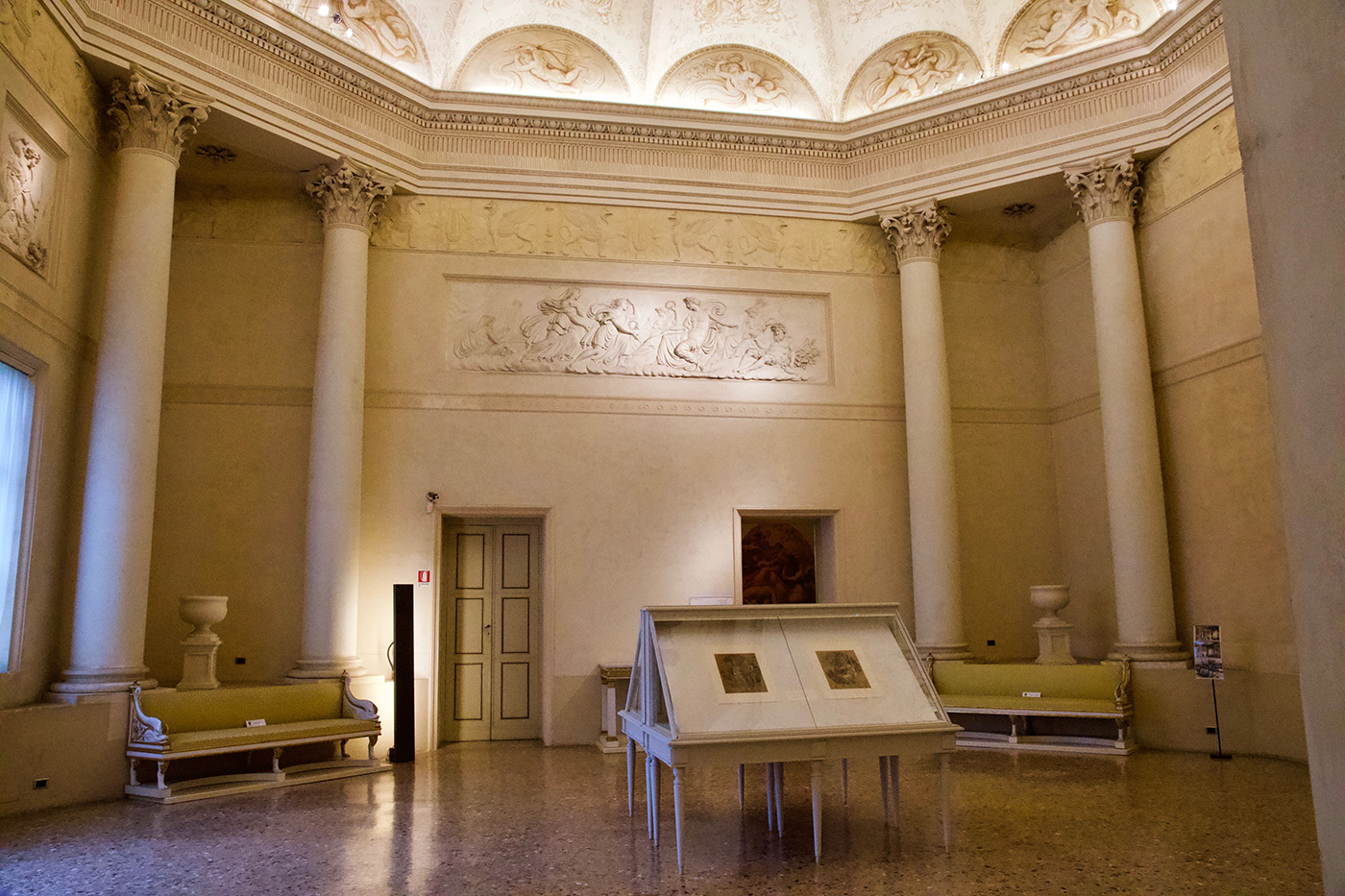 Sala neoclassica di Palazzo Milzetti. Si vedono gli stucchi, alcuni divani, e alcune colonne corinzie negli angoli, così da simulare un ottagono.