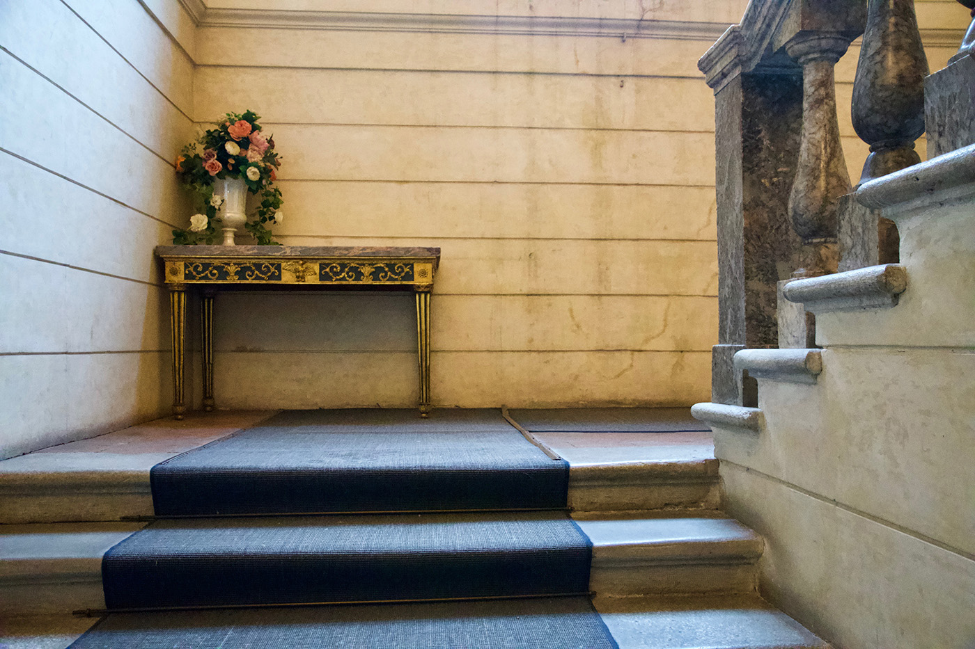 Lo scalone di Palazzo Milzetti. Si vedono le scale, un comodino, e la balaustra di marmo.