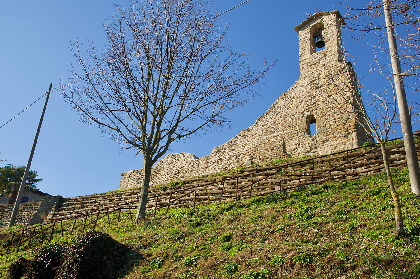 La Chiesa di Sopra, una delle chiese di Casola. Si vede il campanile a vela e i resti della muratura. In primo piano un albero in inverno.